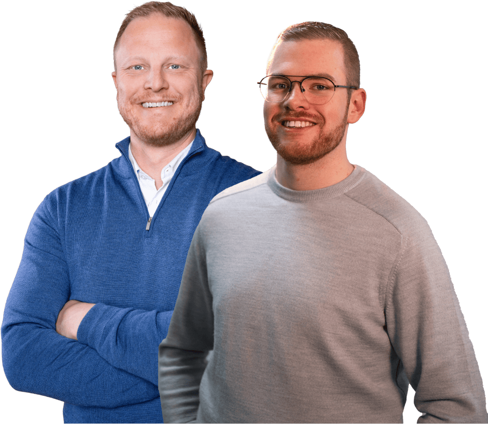 Twee mannen staan naast elkaar, glimlachend en gekleed in casual sweaters, met een groene achtergrond.